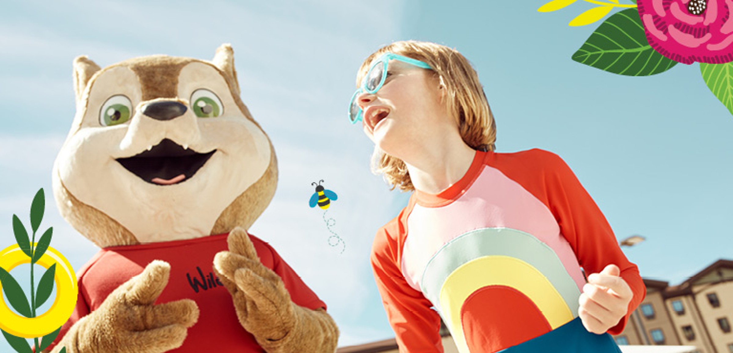 A child wearing sunglasses smiles with Wiley the Wolf at Great Wolf Lodge.